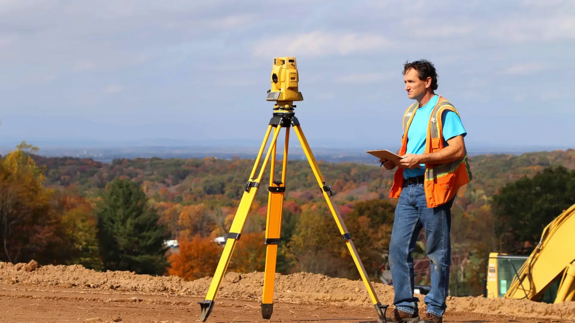 Surveyor on ridge above construction site
